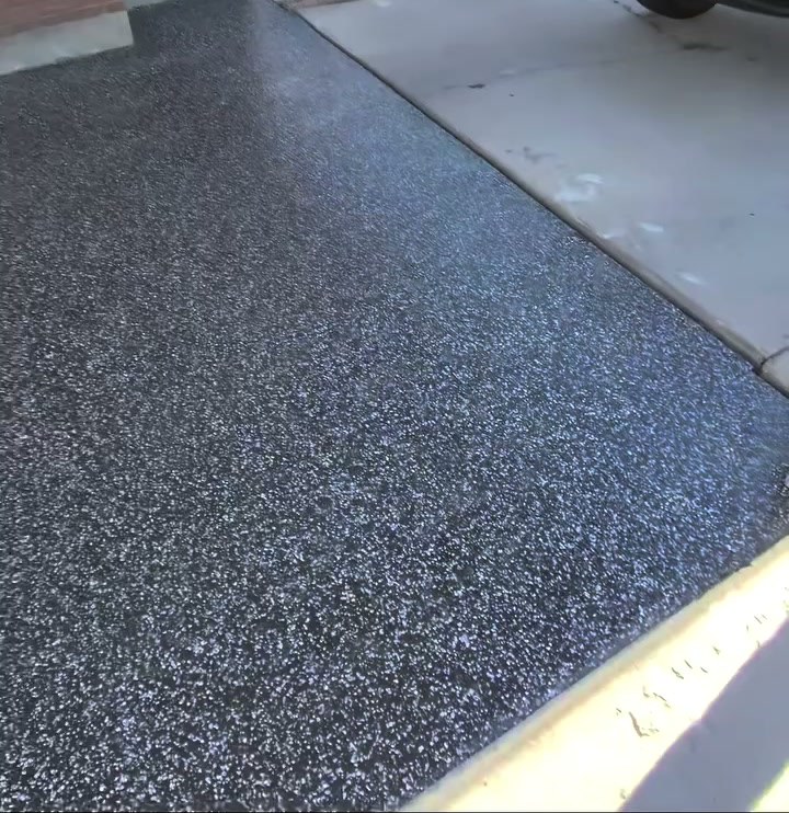 A carport floor in a black, white and grey raven flake blend running out to the concrete apron.