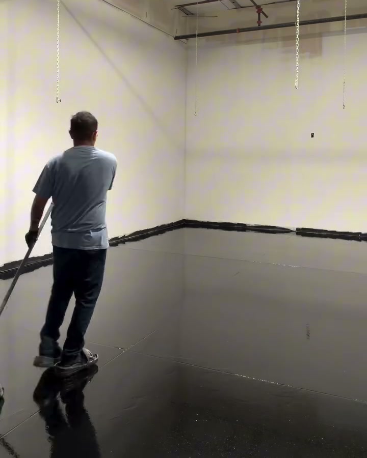 An empty commercial shop with the roller door open and grinding gear standing on the bare slab.